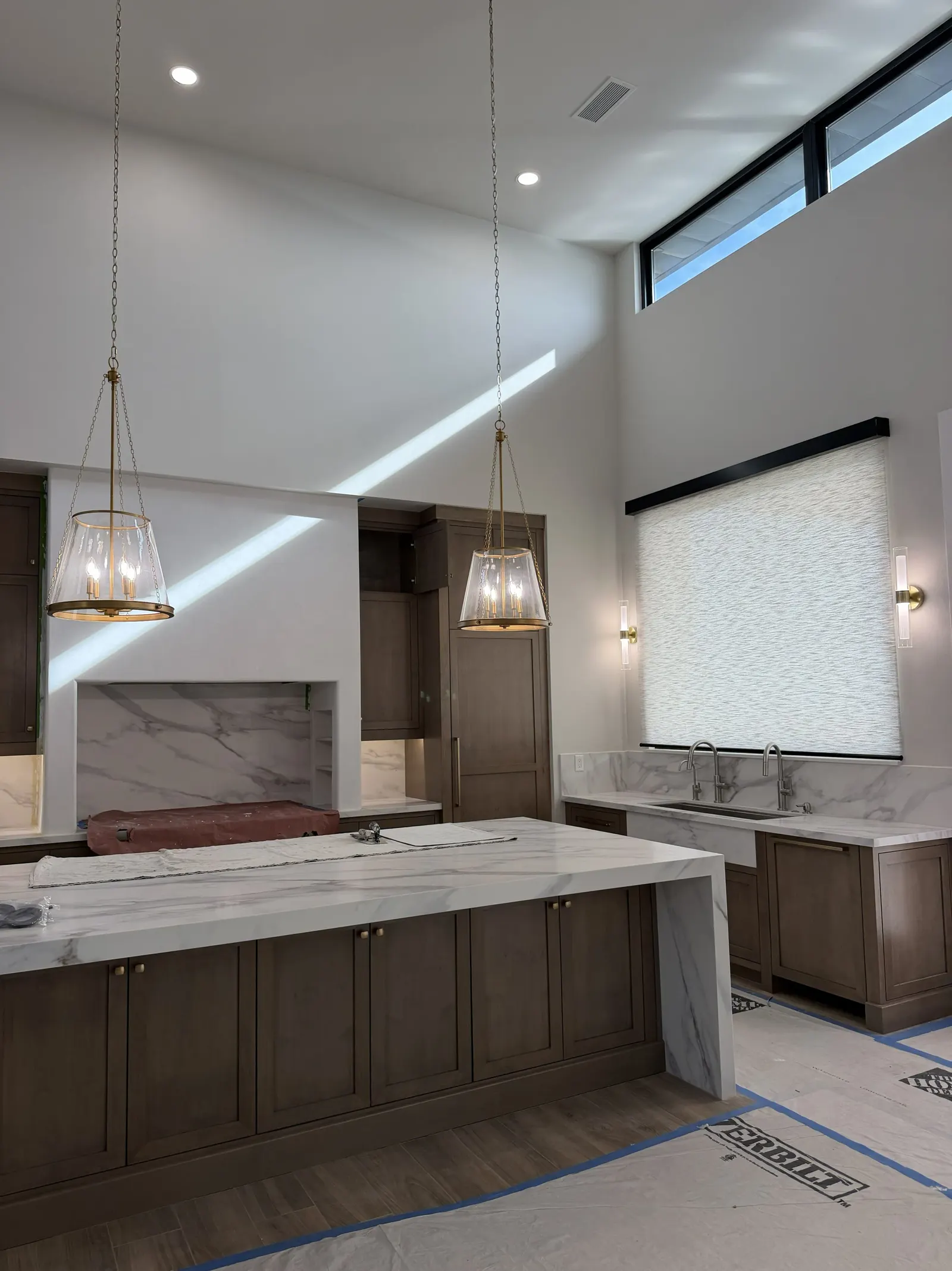Custom home kitchen with brass pendants, marble island, and clerestory windows