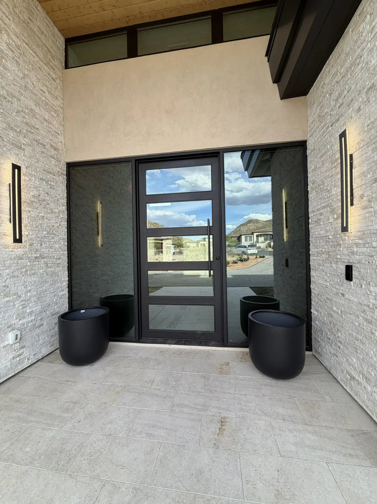 Modern entry with iron door and exterior sconces at a custom home