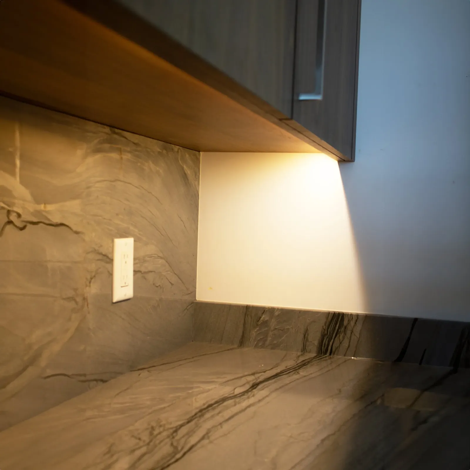 Under cabinet lighting detail on a stone backsplash